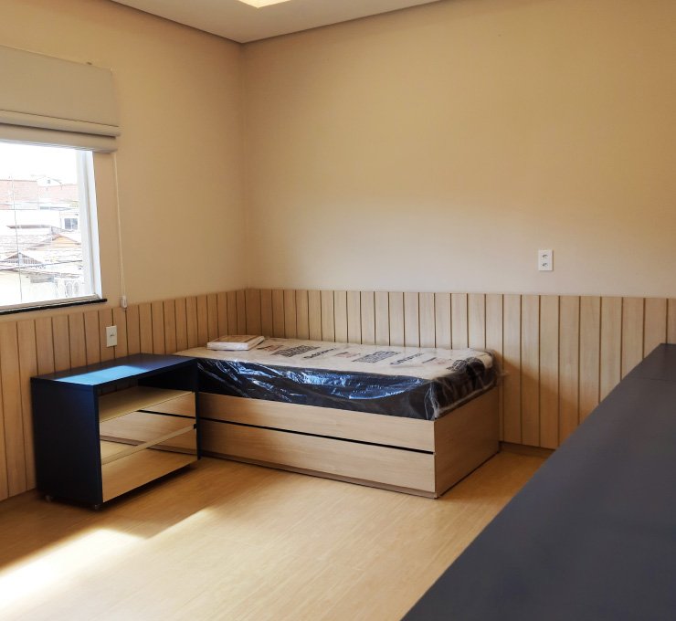 Quarto planejado para menino com cama, gaveteiro e bancada de estudos em tons de amadeirado e azul.